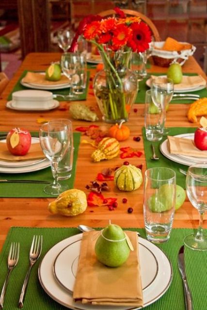 a colorful fall aprty table setting with bright green placemats, faux veggies and fresh apples and pears plus bright florals