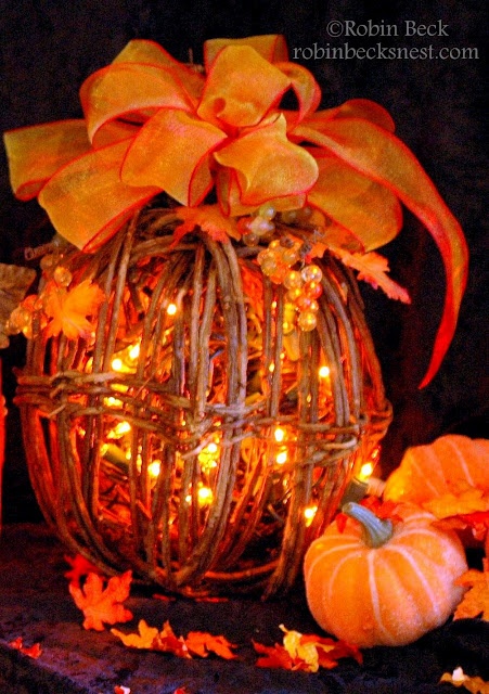 a vine pumpkin with lights, beads and orange ribbons plus faux orange leaves all around
