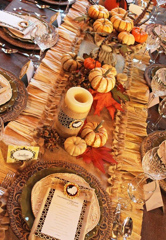 a colorful vintage table setting with a ruffle table runner, faux pumpkins and candles, woven placemats and fall leaves