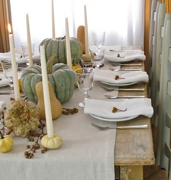 a neutral and natural fall tablescape with faux pumpkins and gourds, tall candles, berries and a neutral fabric table runner