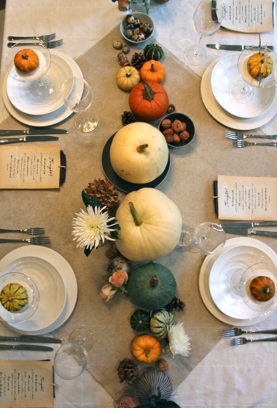 a natural fall tablescape with pumpkins, blooms, pinecones and a neutral tablecloth