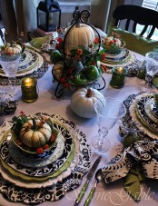 a black and white tablescape spruced up with green touches, with faux pumpkins, berries and leaves