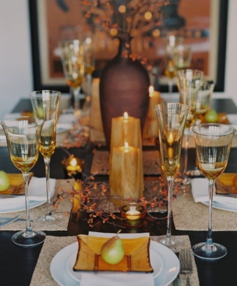 a fall tablescape with amber glass plates, amber candles, berries, and glasses plus pears for each place setting