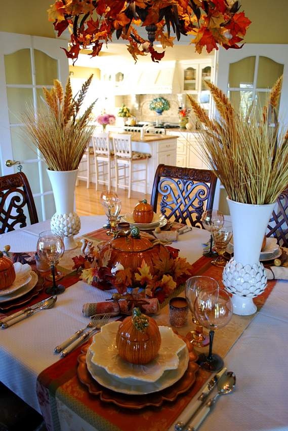 A fall table done with wheat arrangements, colorful textiles, creatively shaped plates, pumpkins pots and much more
