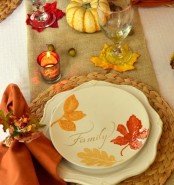 a fall tablescape with a burlap runner, woven placemats, bright napkins and plates with printed leaves