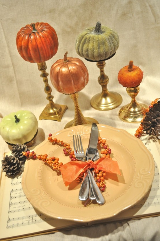 a simple fall place setting with faux pumpkins, a plate on a music note placemat, pinecones and berries