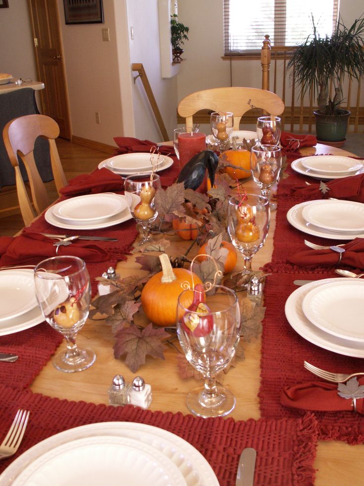 a bright fall tablescape with red textiles, fall leaves, pumpkins and a blackbird will do for a Halloween party, too