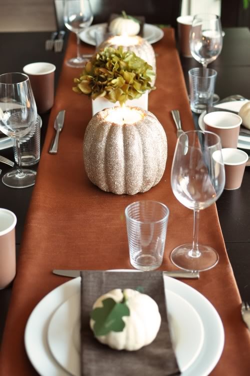 a bold fall tablescape with a rust table runner, white pumpkins with leaves and green hydrangeas
