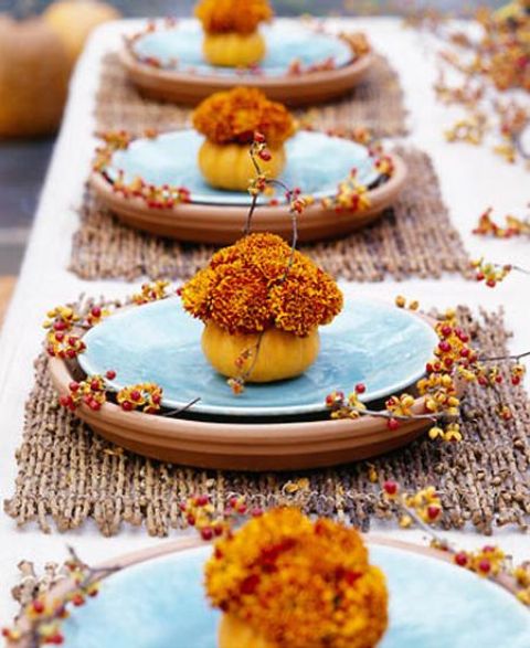 a colorful fall tablescape with stick placemats, bright blooms and blue plates