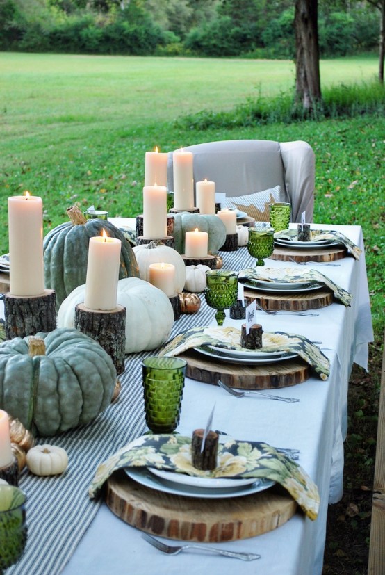 a natural fall tablescape with a striped table runner, heirloom pumpkins and candles on tree stumps