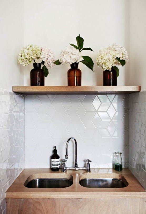 a small kitchen nook with glossy white geometric tiles, with sinks placed into plywood and a built-in wooden shelf is amazing
