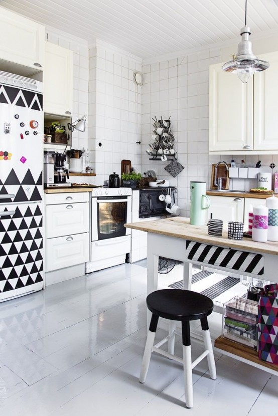 a black and white Scandinavian kitchen a black and white geo print fridge and a striped table, white square tiles and metal pendant lamps