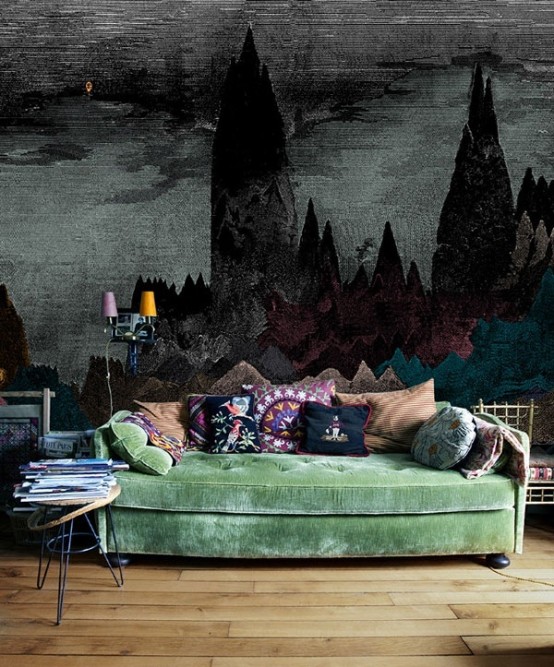 a Gothic living room with a touch of bright color - a green sofa with colorful pillows and a statement moody wall mural