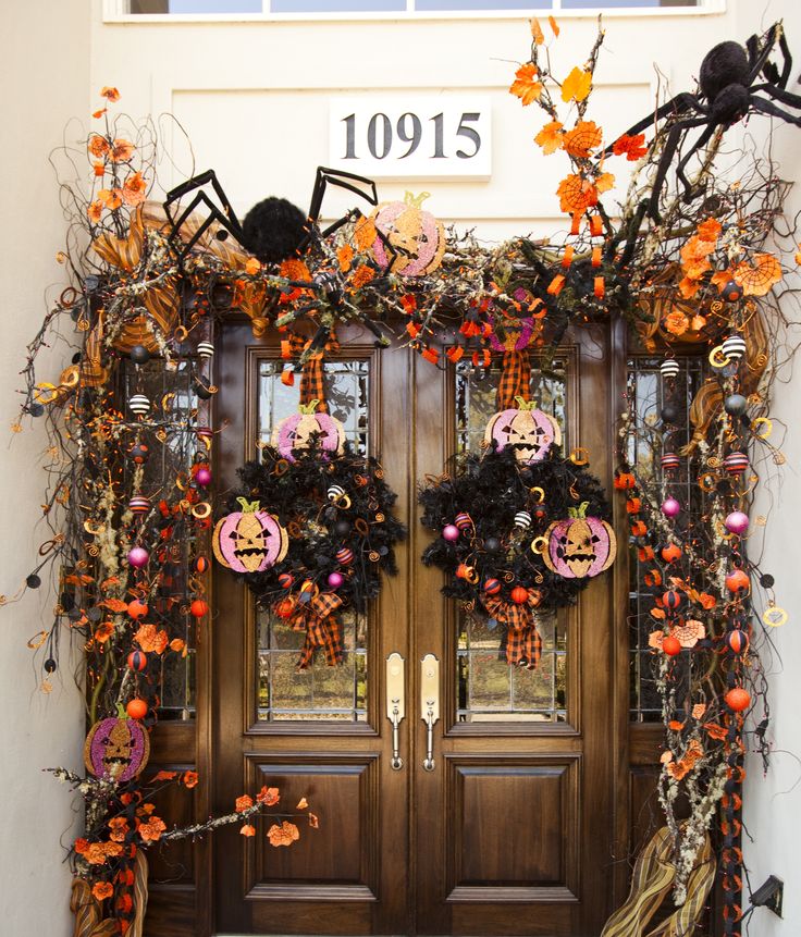A super bright Halloween front door decorated with black spiders, bright leaves, plaid ribbons, jack o lanterns, ornaments and skulls