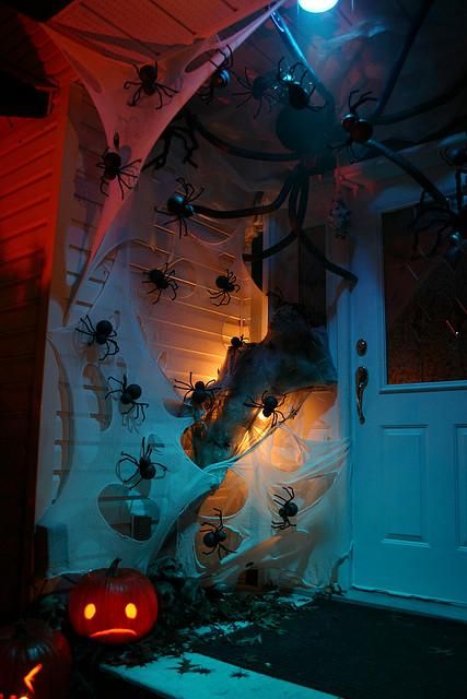 Spooky Halloween front door decor with lots of spiders, spiderweb and a jack o lantern is a very cool and fresh idea