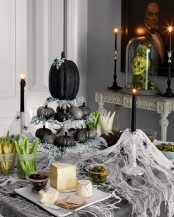 cheesecloth, black candles, a tiered stand with black and silver glitter pumpkins plus some greenery for a Halloween party