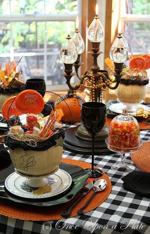 a bright Halloween tablescape in black, orange, white, with a candelabra, black goblets, orange pumpkins and plaid textiles