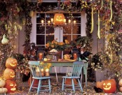 rustic Halloween table decor done with candle lanterns, crows, pumpkins and jack-o-lanterns, fall leaves and lights