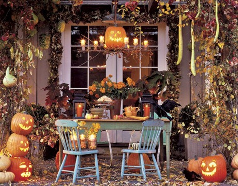Rustic Halloween table decor done with candle lanterns, crows, pumpkins and jack o lanterns, fall leaves and lights