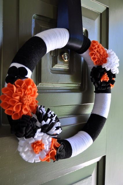 a bold Halloween wreath in black and white, with black, white and orange fabric flowers is a cool idea for Halloween