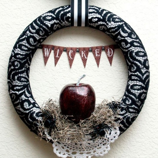 a bold Halloween wreath wrapped with black lace,w ith a doily, faux spiders and a glitter poisoned apple plus a banner is great for Halloween decor