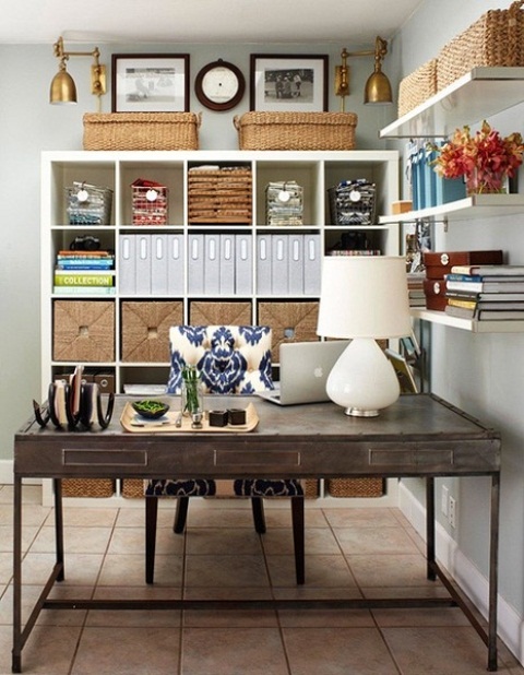 A neutral rustic home office with open shelves, an open storage unit, a dark stained desk, a black chair and cool decor