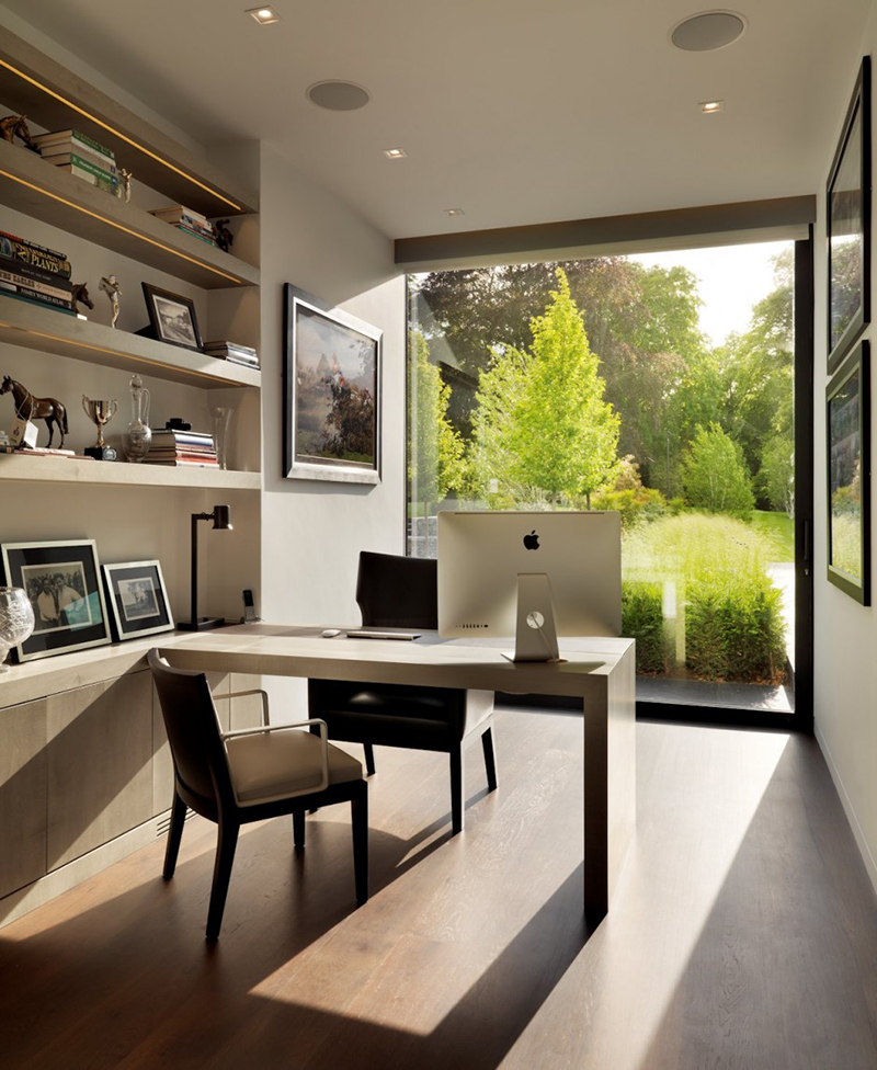A small and chic modern home office with a glazed wall to the garden, built in shelves, a built in desk and a couple of chairs is amazing