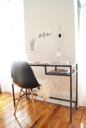 a small Scandinavian working nook with a black Vittsjo table as a desk with storage, a black chair, a gallery wall of drawings