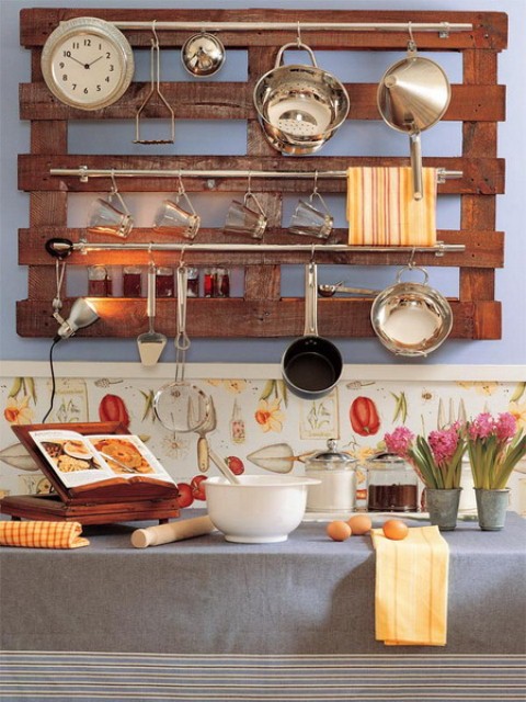 A wall mounted pallet with railings that feature holders for all kinds of stuff, from clocks to utensils is a cool idea for a rustic space