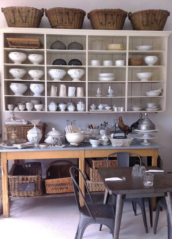 A large open wall mounted shelf with baskets on top and an additional kitchen island with a storage space for holding a lot of things