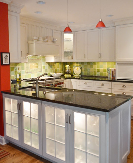 A large kitchen island with storage space and built in lights plus fridges for storing wine and other alcohol