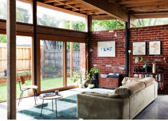 an indoor-outdoor living room with a red brick statement wall and a glazed wall with sliding doors