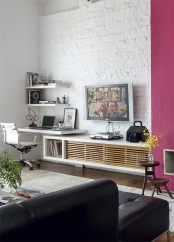 a contemporary living room with a white brick wall and a fuchsia accent plus dramatic dark furniture
