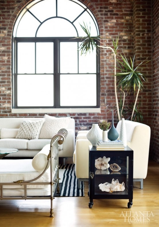 a chic living room with red brick walls and elegant white upholstered furniture for a contrasting combo
