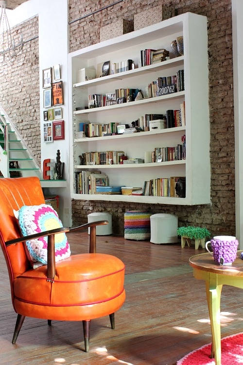 a living room with original brick walls, colorful items and accents plus artworks