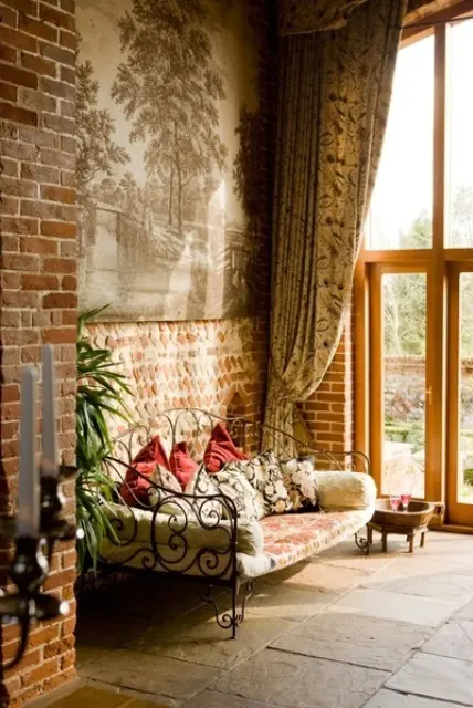 a vintage refined living room with brick walls, a forged bench and printed curtains