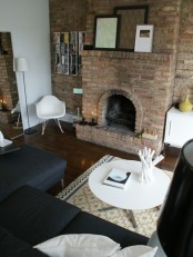 a black and white living room is spruced up with a textural brick statement wall – it adds color and texture