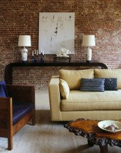 a refined living room is made less formal with a red brick statement wall, which also brings texture