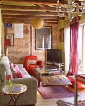 a super colorful living room with a red brick statement wall and super bright furniture