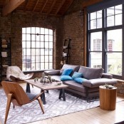 rough brick walls contrast the soft and neutral upholstered furniture and pillows