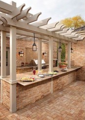 an outdoor bbq zone built of stone and brick, with a grill, lanterns, a cooking countertop and a meal space