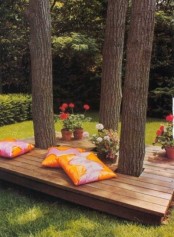 a contemporary deck with colorful pillows and potted blooms – the deck is integrated right into the trees