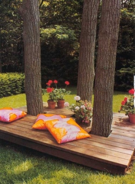 A contemporary deck with colorful pillows and potted blooms   the deck is integrated right into the trees