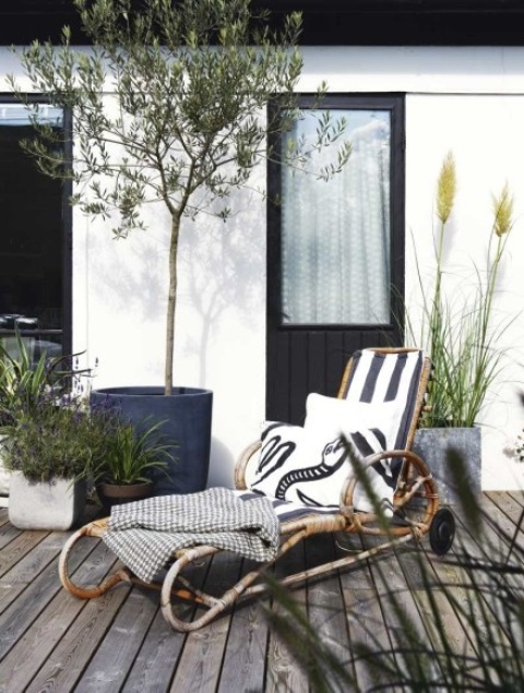 a rattan lounger with casters and elegant upholstery, pillows and blankets is a chic modern idea with a natural feel