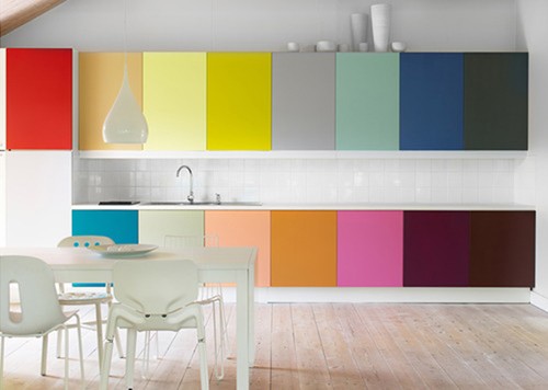a minimalist rainbow kitchen with sleek cabinetry, a neutral dining set and a pendant lamp