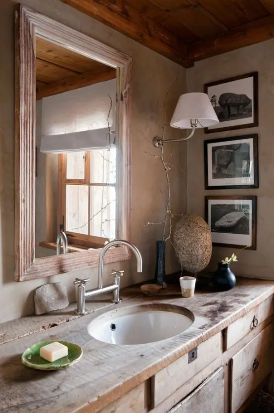a rustic meets vintage bathroom with a weathered wood vanity and a wood frame mirror