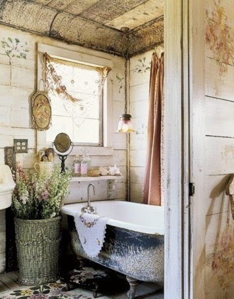 a vitnage farmhouse bathroom with whitewashed wooden planks, a vintage bathtub and a large basket