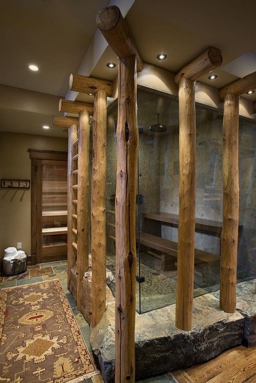 a rustic bathroom with a stone and tile shower plus logs cladding the shower