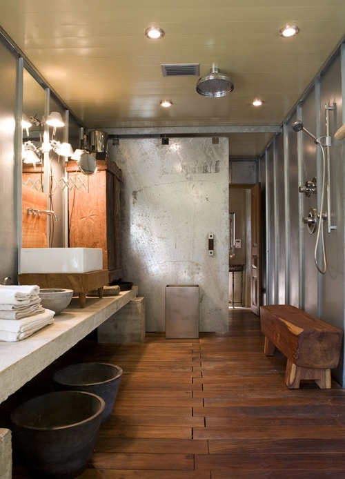 an industrial bathroom with much wood, metal and concrete plus lamps all over
