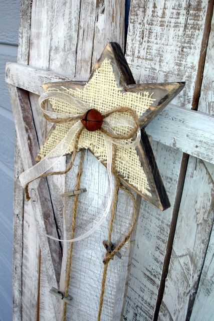 a wooden star Christmas decoration with burlap, a bell and a twine bow for a rustic feel
